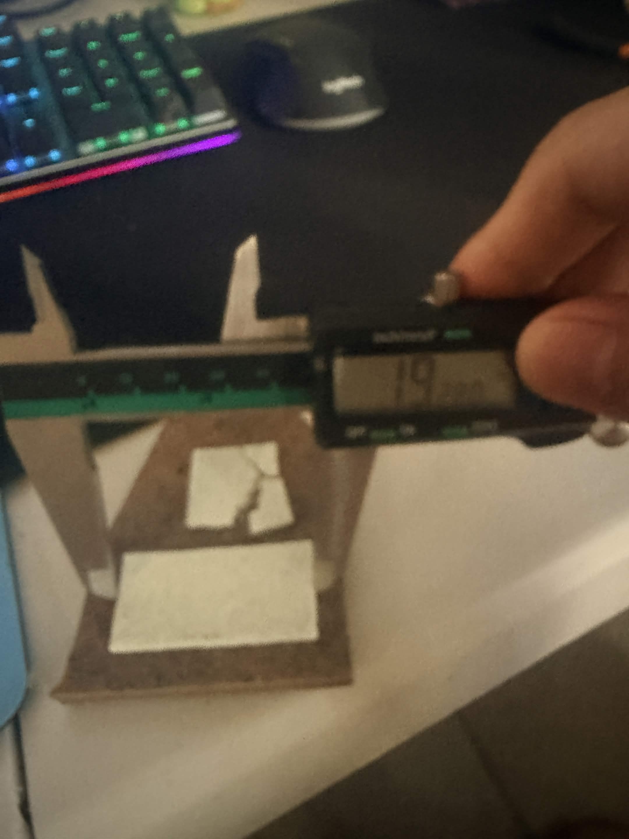 Digital calipers measuring a fired test article on a desk.